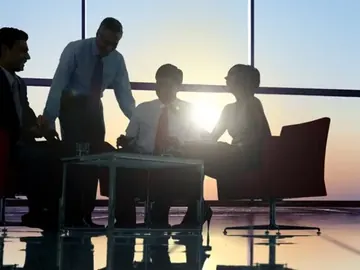 Consultants around a meeting table, silhouetted against an office window